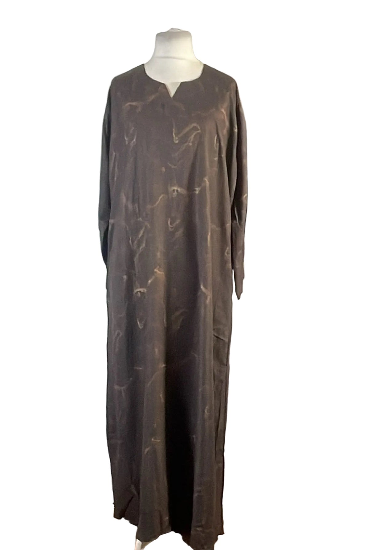 A long-sleeved, floor-length brown abaya dress with a subtle gold abstract pattern, displayed on a mannequin against a white background.