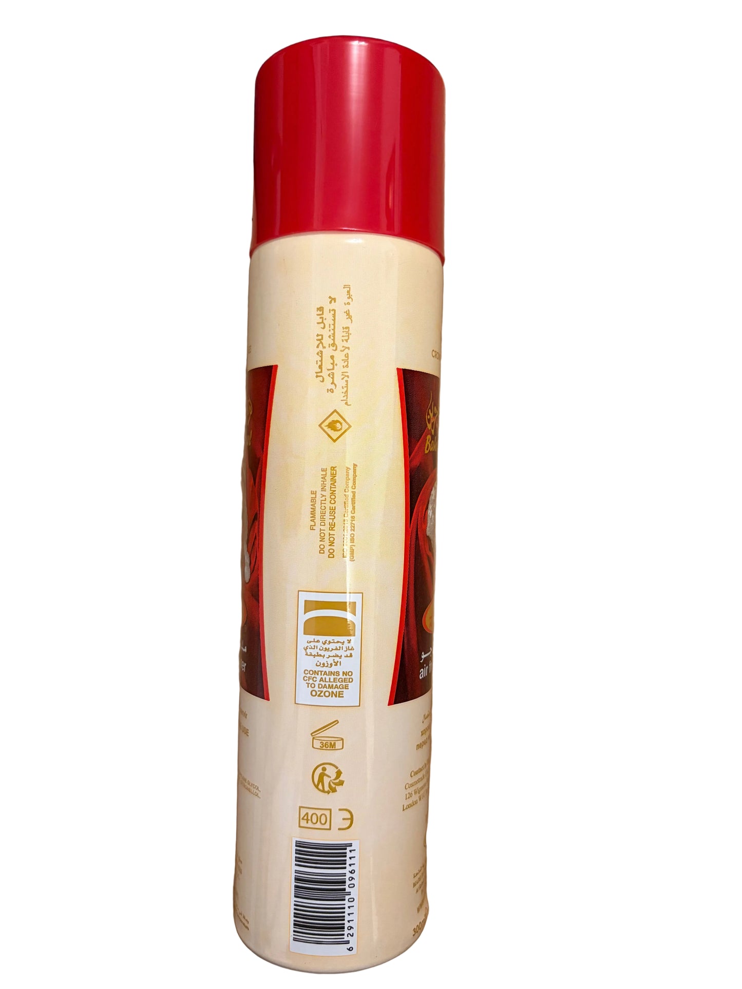 A cylindrical can of hair color or dye, shown upside down on a wooden floor. The can has a cream-colored body with a bright red cap and a label featuring red and gold graphics.