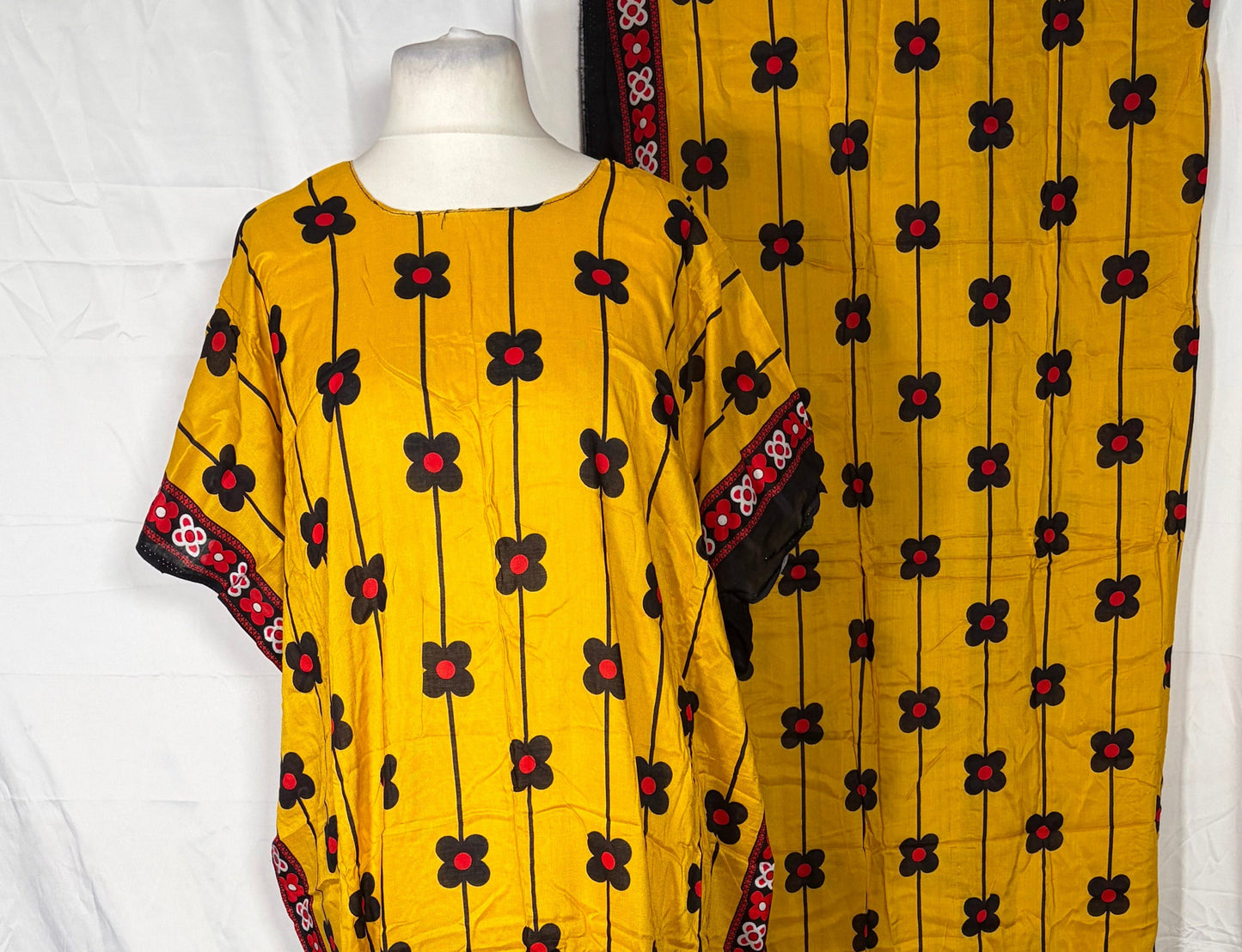 Yellow fabric with black and red patterns draped over a white surface