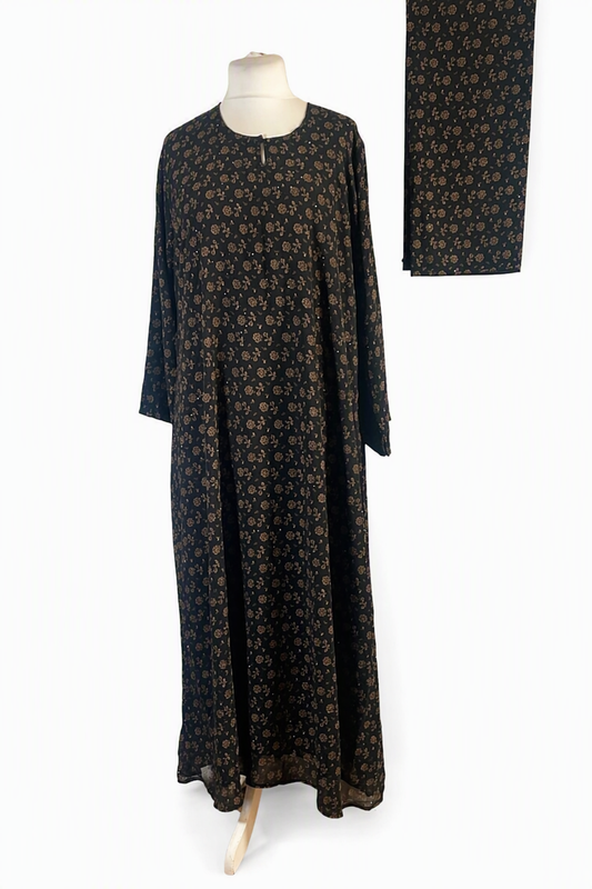 A long-sleeved black maxi dress with a small brown floral pattern, displayed on a mannequin against a white background, with a matching fabric swatch shown in the upper right corner.