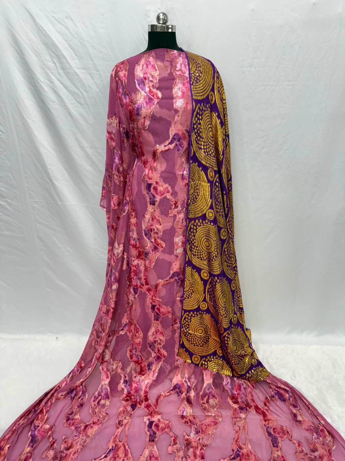 Mannequin wearing a vibrant dress with pink floral pattern and purple and gold abstract design.