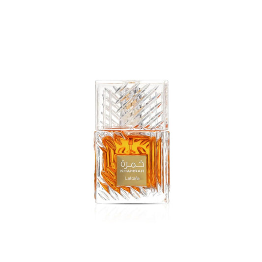 A clear glass perfume bottle with a geometric patterned cap, filled with amber-colored fragrance and featuring a gold label with Arabic text and the brand name 'Lattafa'.