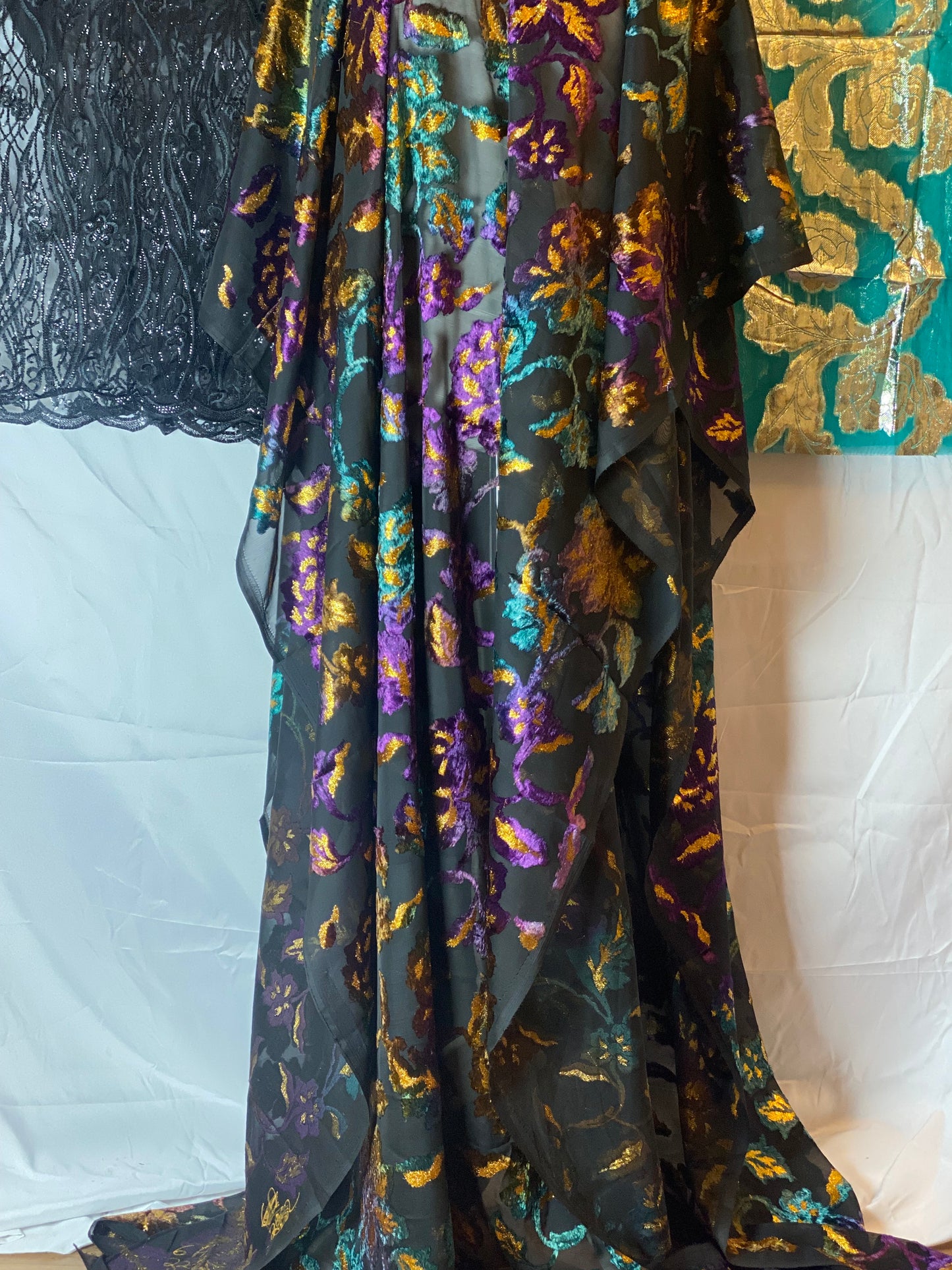 Maqbal Dirac Black fabric with gold and purple floral patterns on a white background