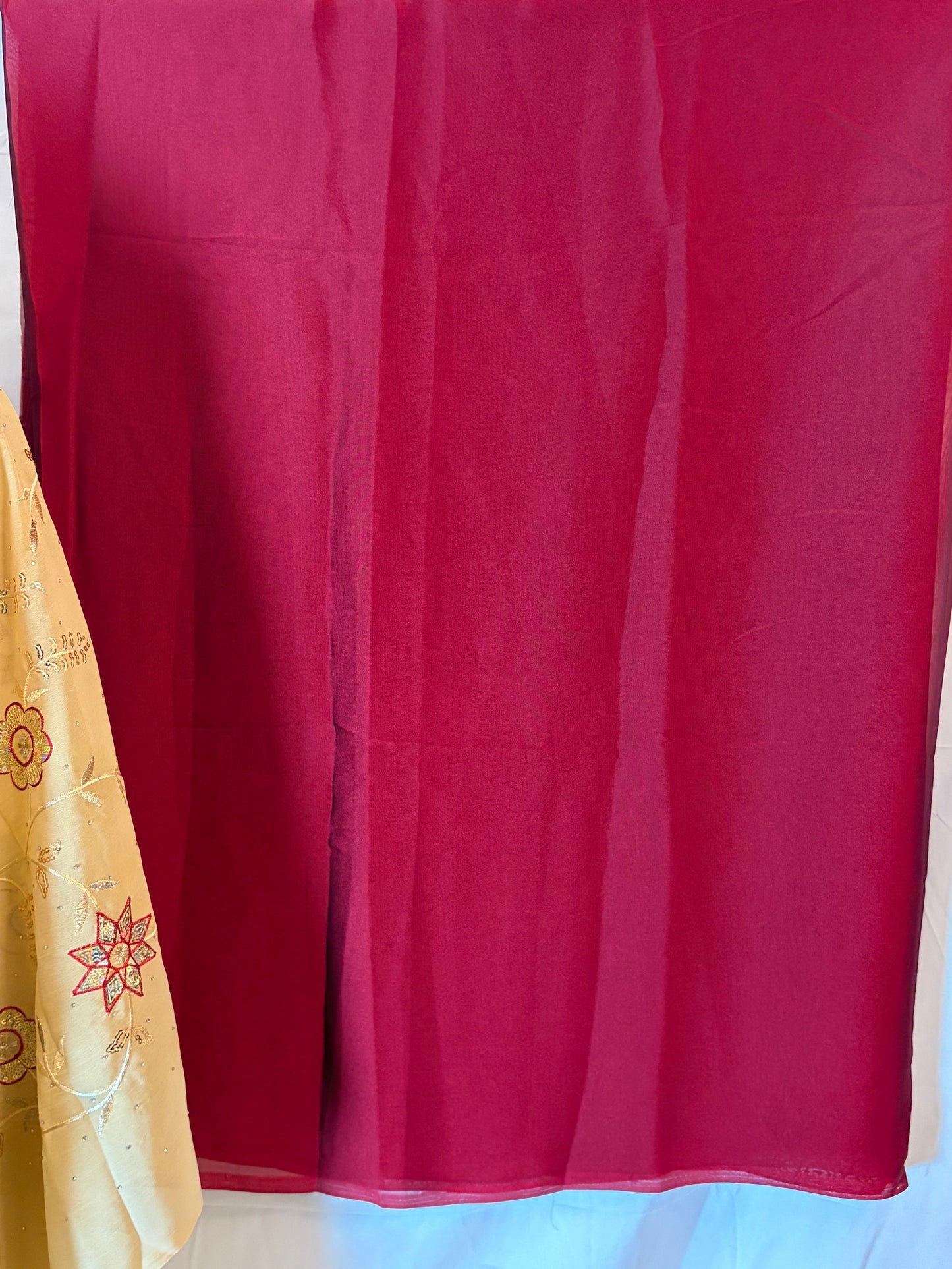 Red fabric with a white border and a folded beige item on a white background