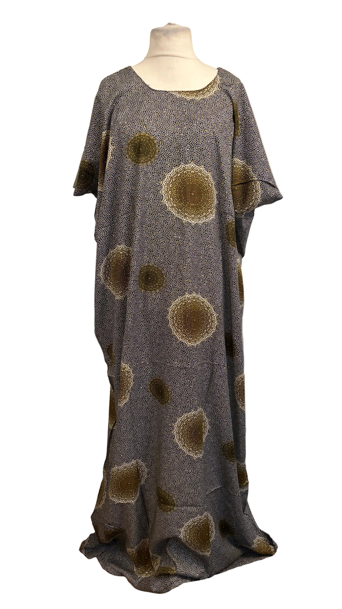 A loose, floor-length Somali Baati dress displayed on a mannequin against a plain white background. The dress has a textured gray base with a pattern of large, hand-drawn style brown and beige circular spots.