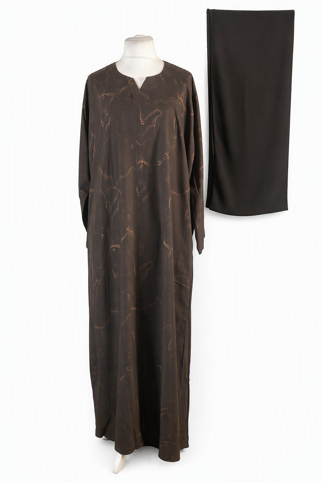 A dark brown long-sleeved abaya dress with a subtle gold abstract pattern, displayed on a mannequin next to a matching solid dark brown skirt.