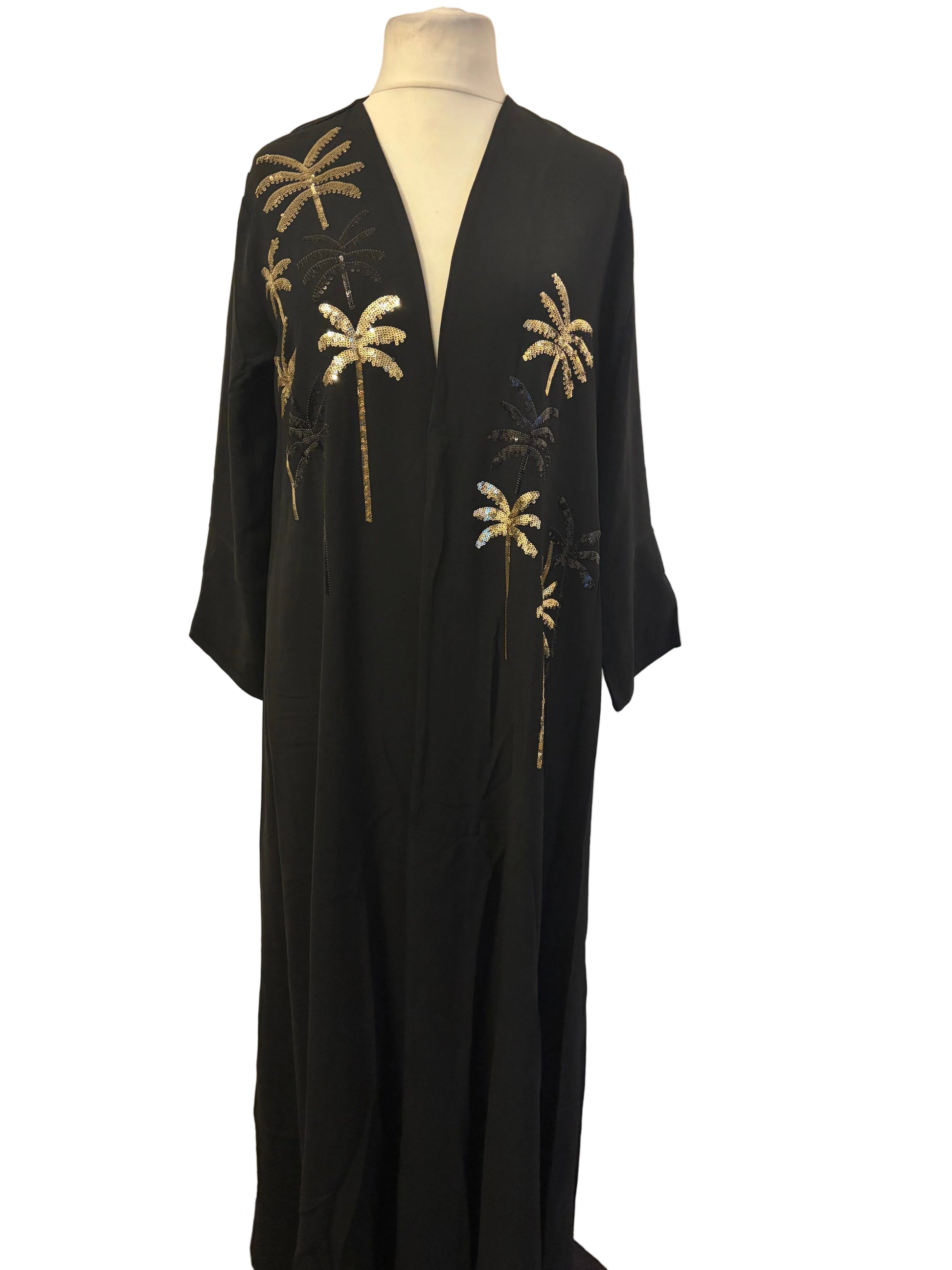 Black dress with palm tree embroidery on a mannequin against a white backdrop