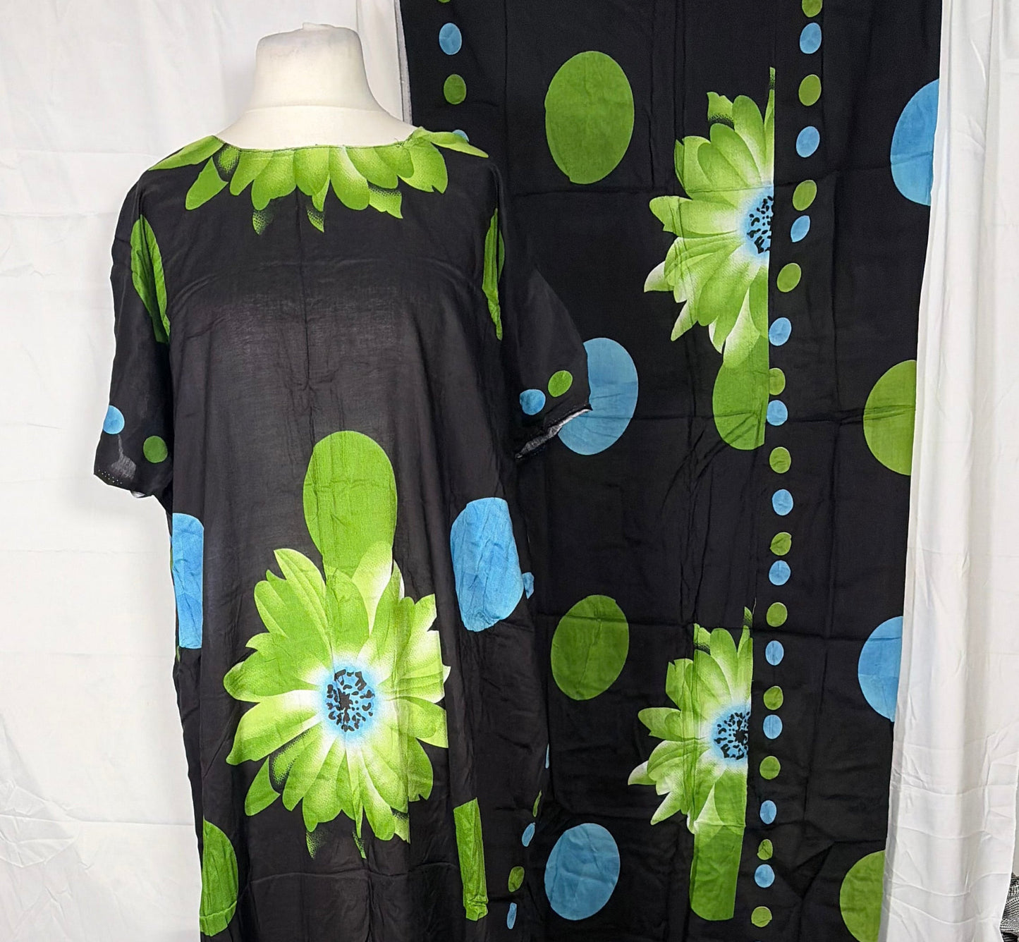 Black dress with green and blue floral patterns on a white background