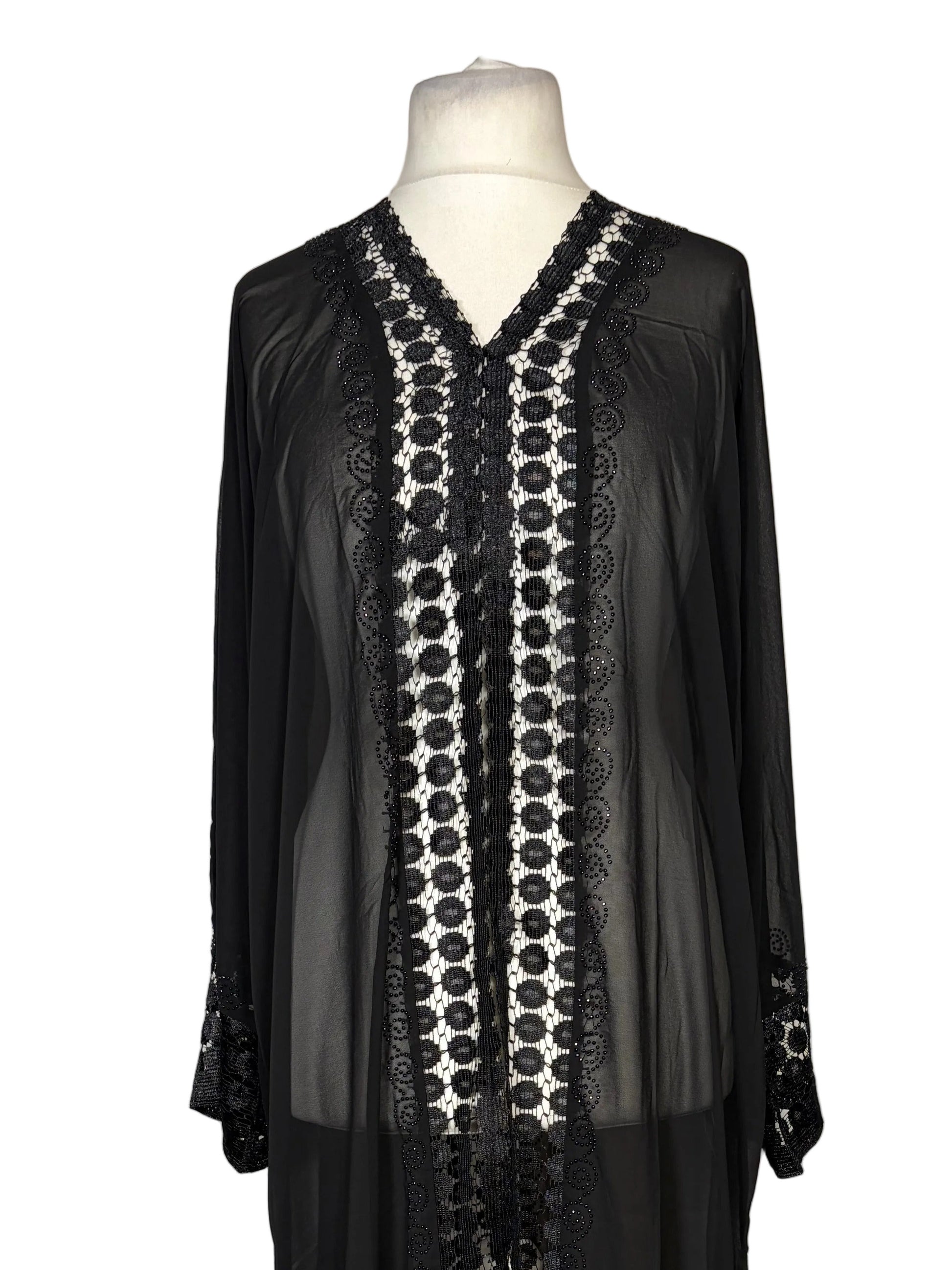 Black dress with intricate white pattern on a mannequin against a white background