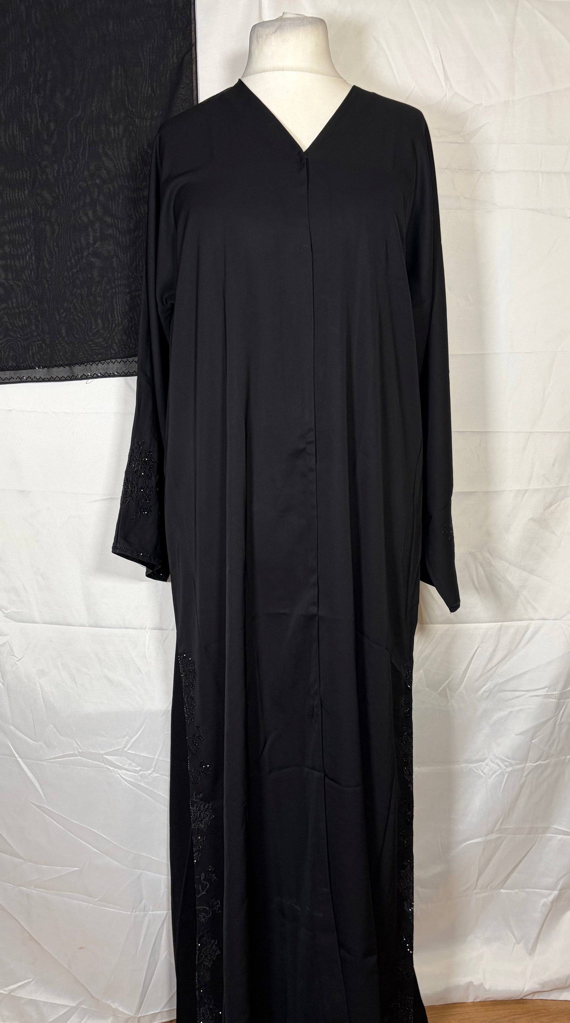 Black Open abaya on a white sheet with a wooden floor background