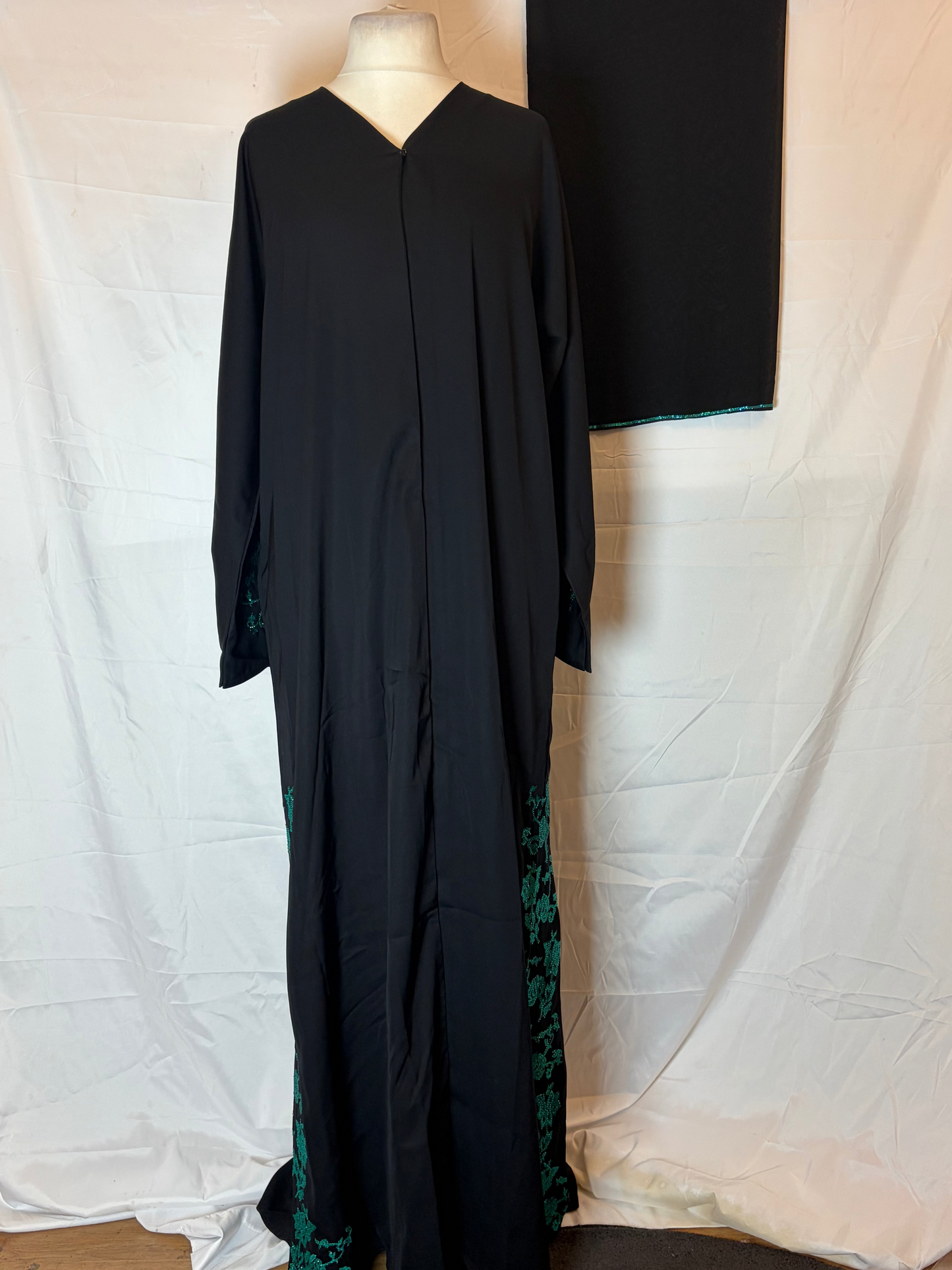 Black abaya with blue embroidery on a white background
