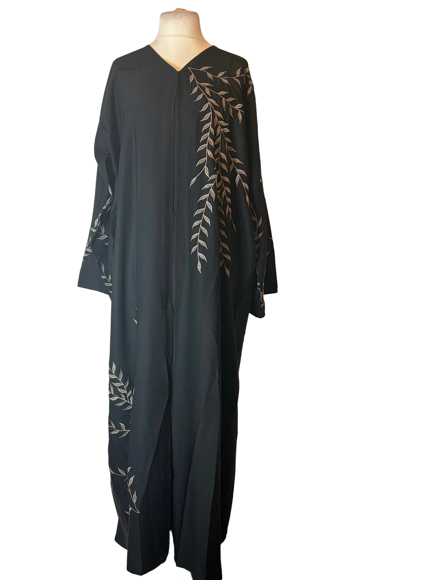 Black abaya with white floral embroidery on a mannequin against a white backdrop