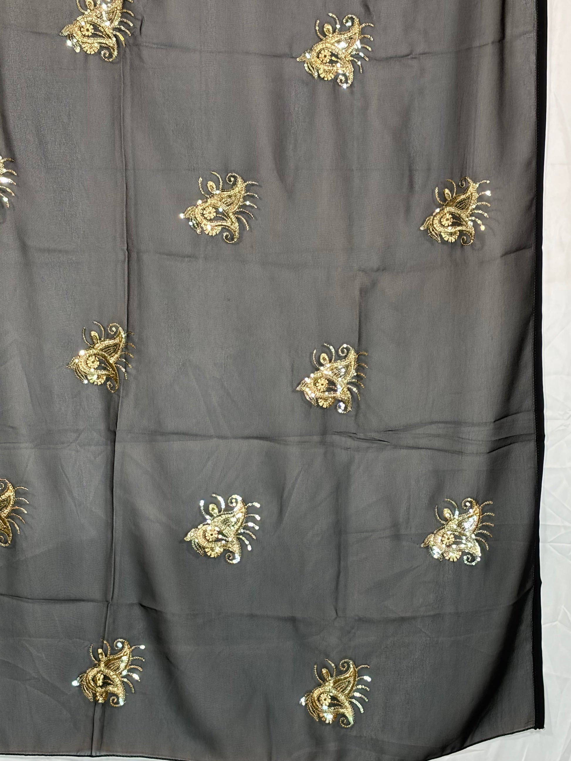 Black fabric with gold embroidered patterns on a white background