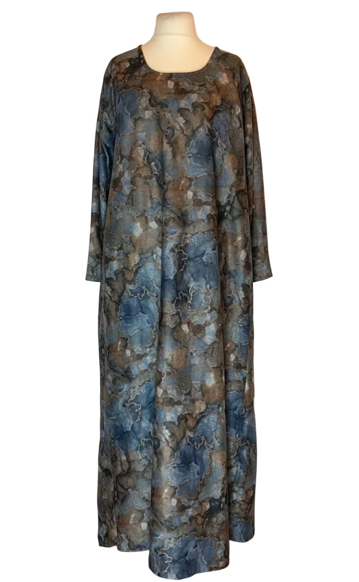 Long, patterned dress on a mannequin against a white draped background