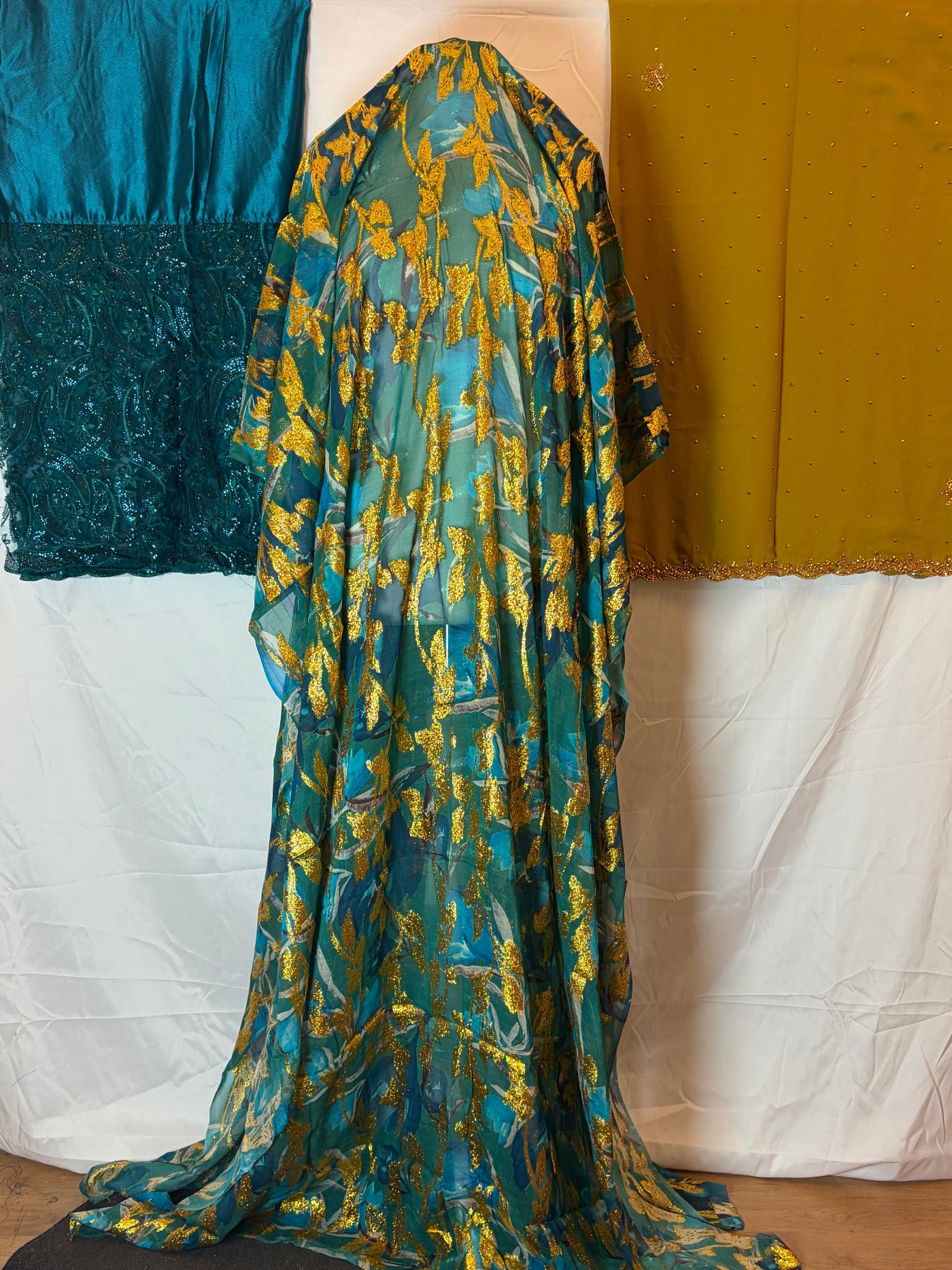 Blue and gold Somali Dirac fabric draped over a surface with a white pillow in the background