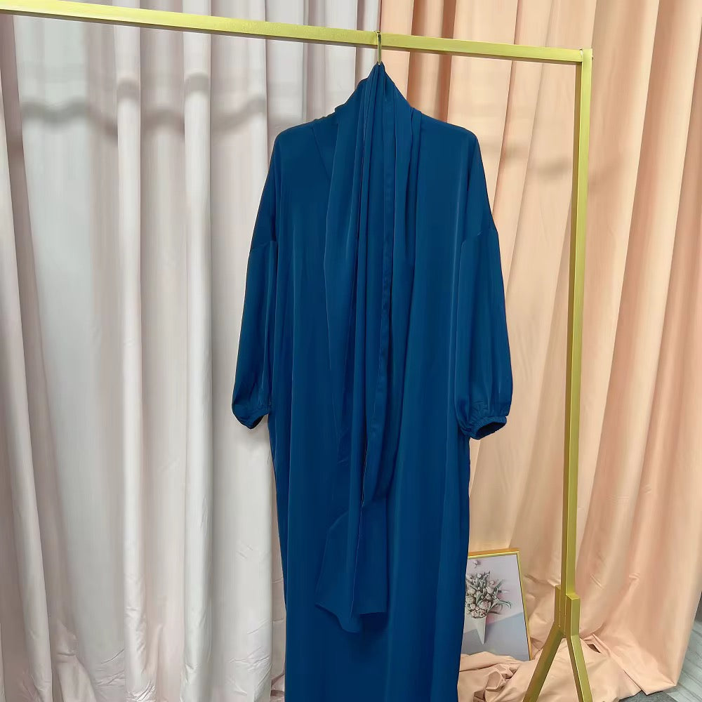 Blue abaya dress hanging on a rack against a curtain backdrop