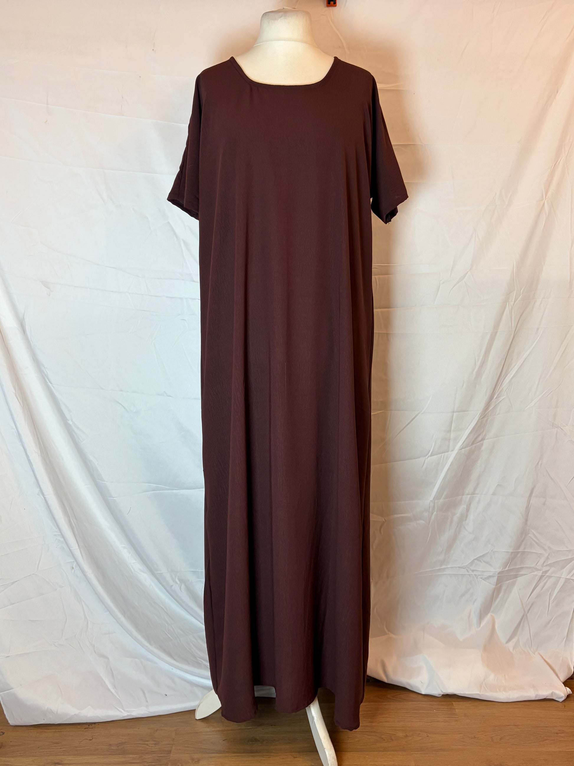 Brown dress on a mannequin against a white bedspread background