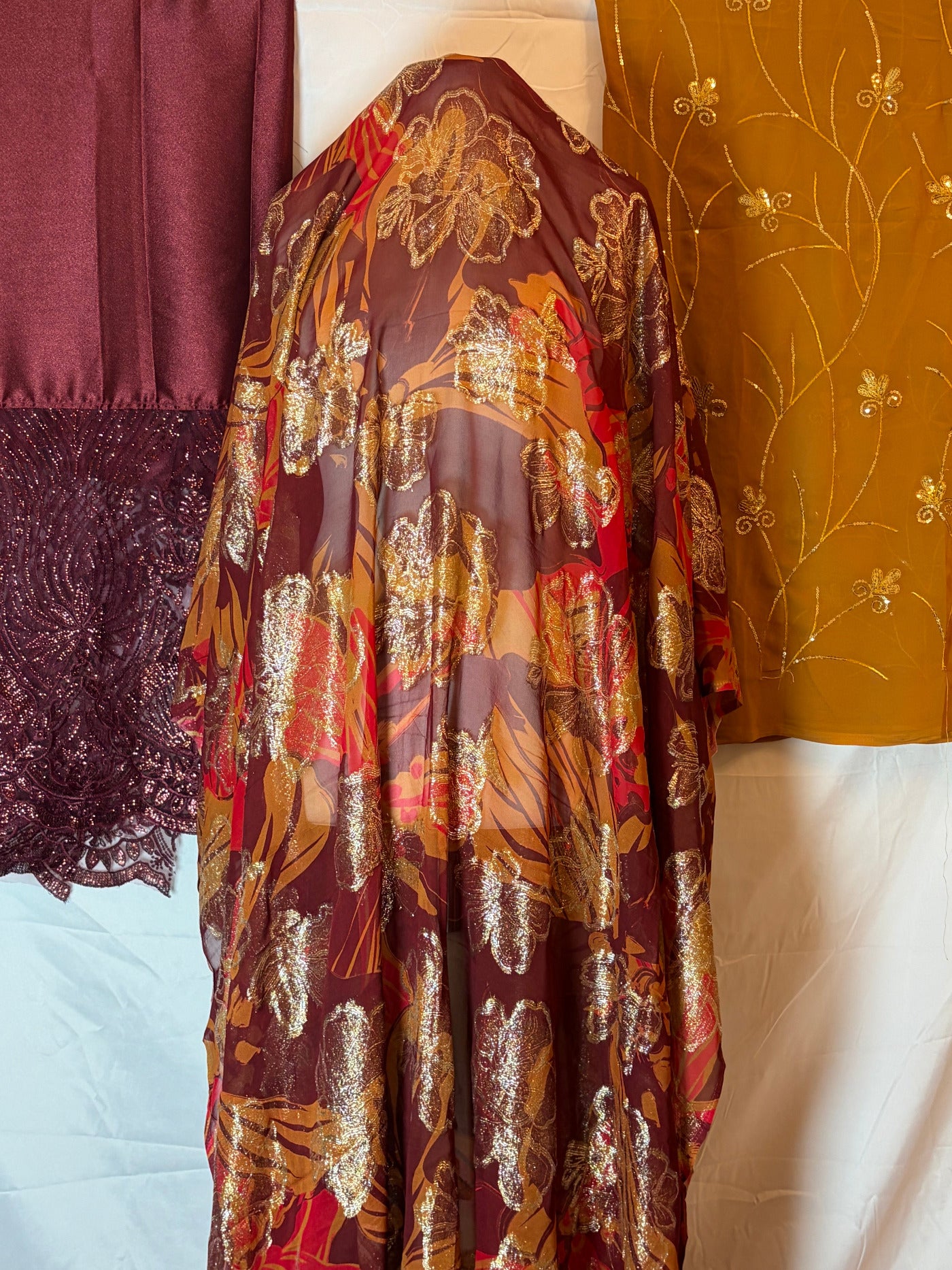 Close-up of patterned fransawi Dirac fabric with gold, red, and brown colors on a white background