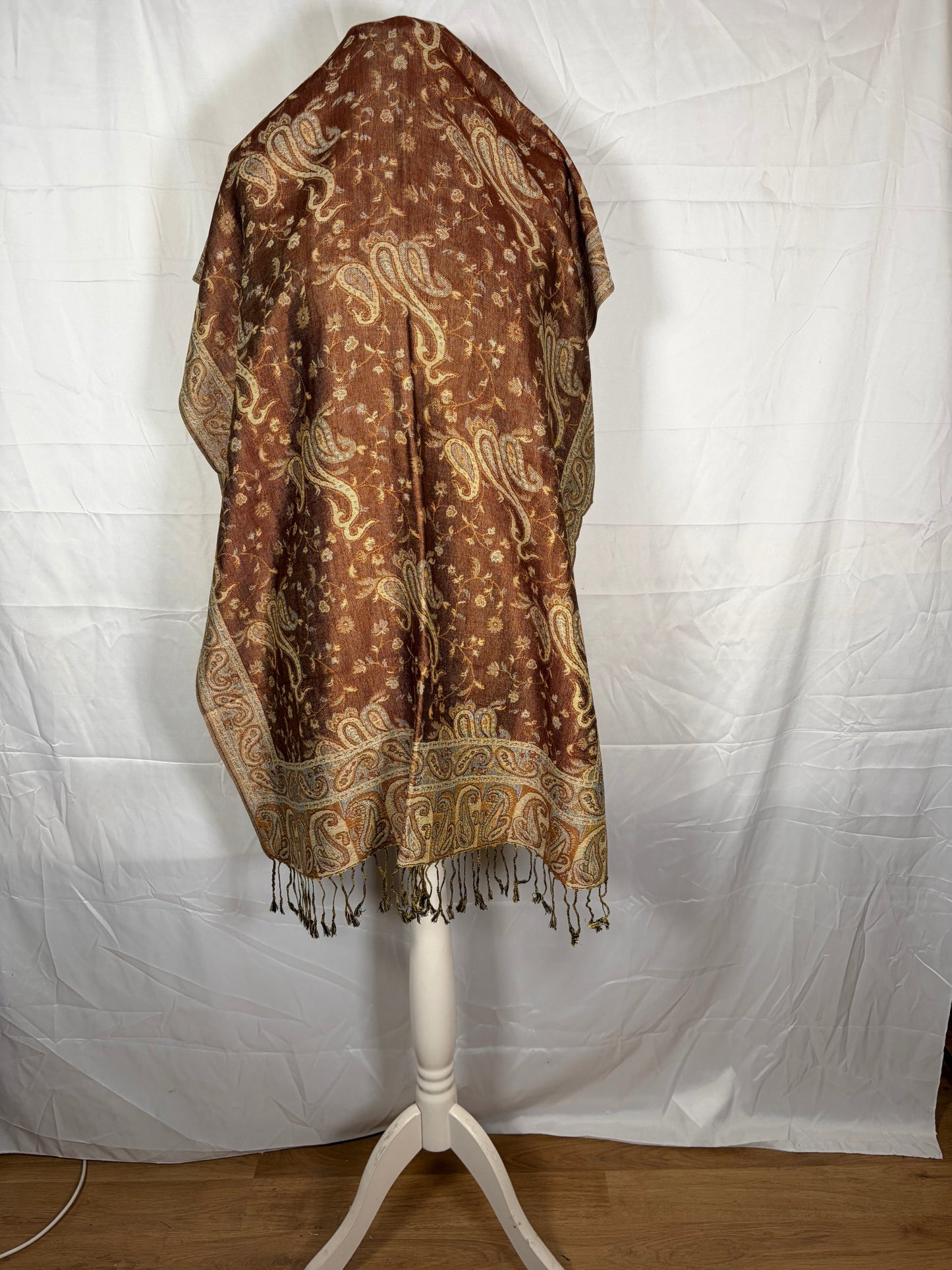 Brown patterned fabric draped over a white stand on a white background