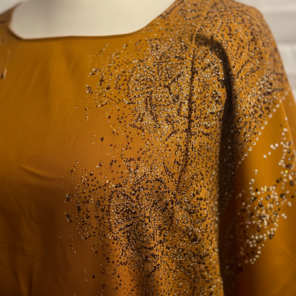 Mustard yellow baati with black bead embellishments on a white background