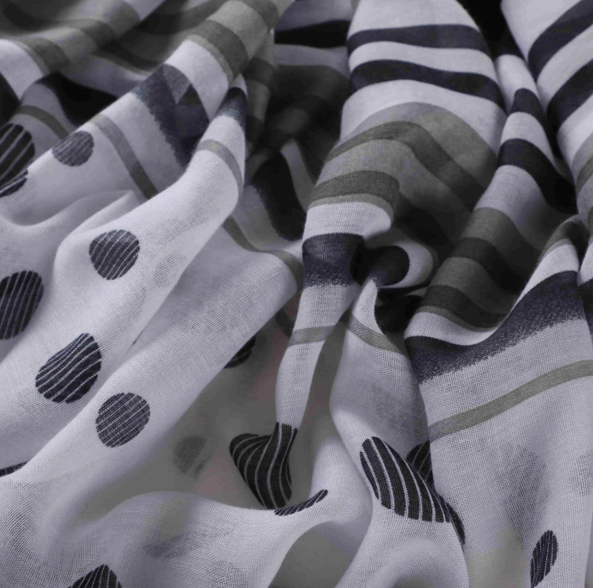 Close-up of patterned fabric with polka dots and stripes on a white background