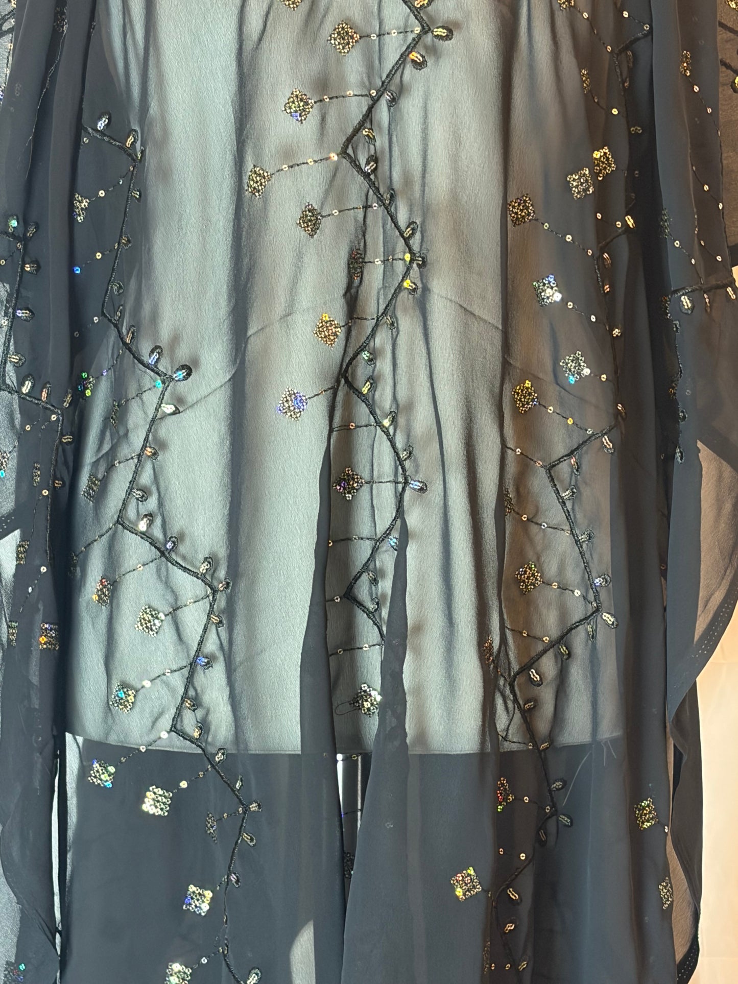 Black Garbasaar fabric with gold embroidery and sequins on a beige background