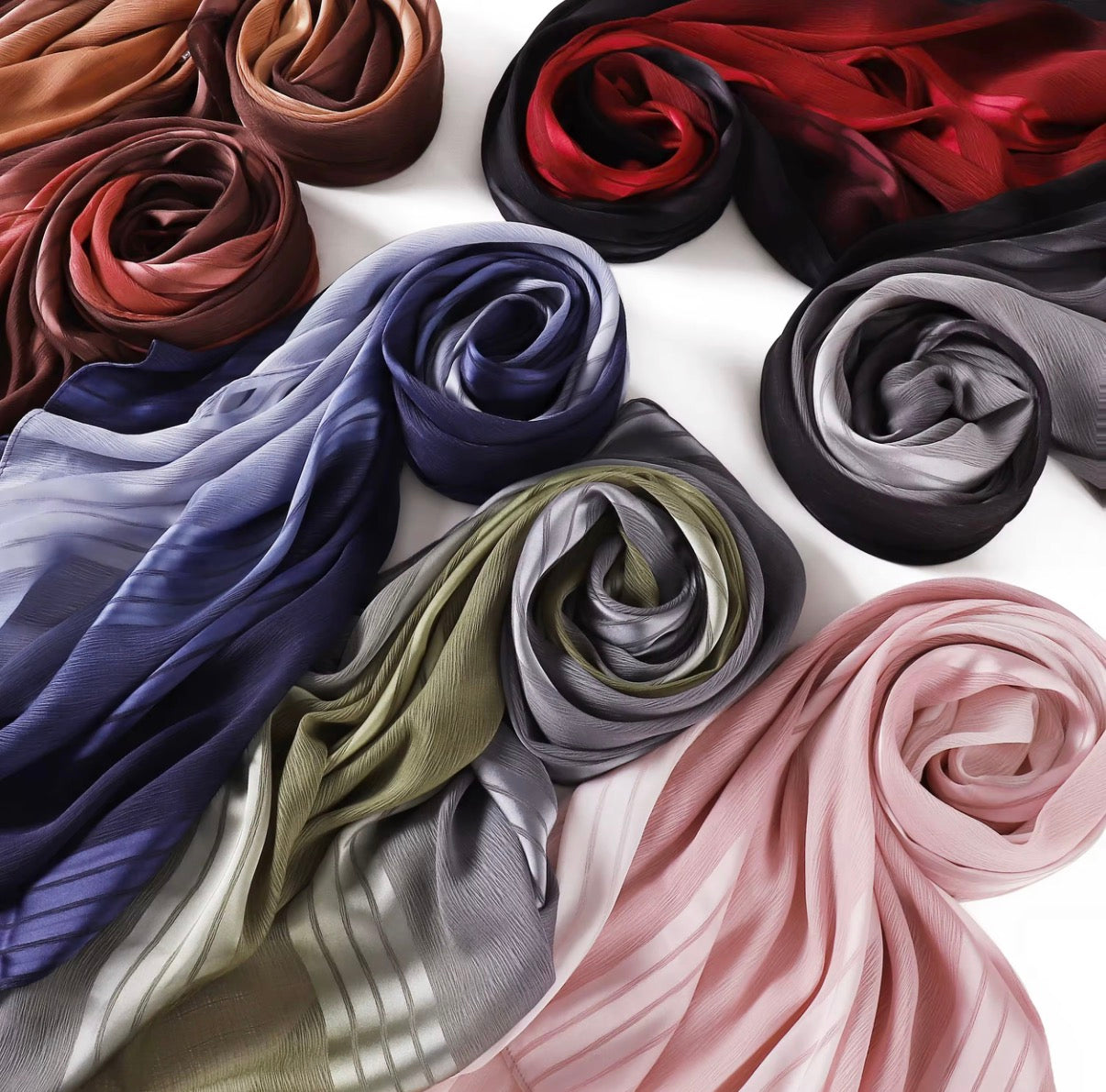Collection of rolled-up Hijab in various colors on a white background