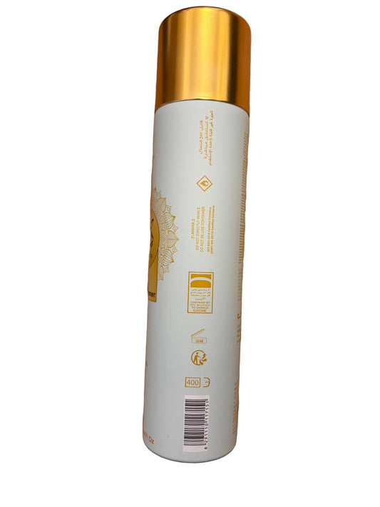 A tall cylindrical bottle with a metallic gold cap and a white body, featuring gold printed graphics and text, lying on a wooden floor.