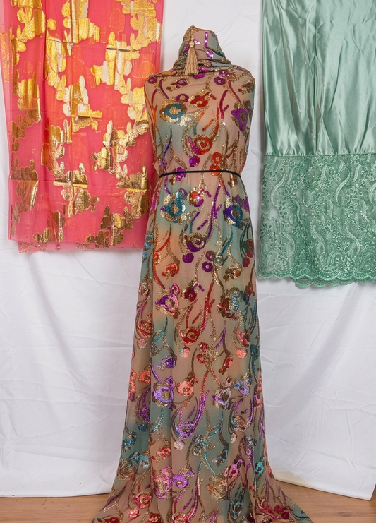 Colorful embroidered dress with a pink and gold patterned fabric and green lace garment on a white background.