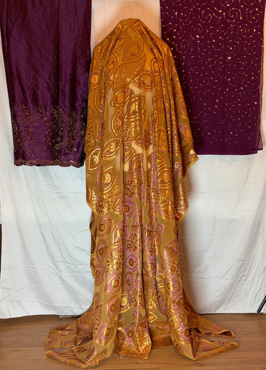 Gold and purple somali Dirac fabric on a white surface with a wooden frame.