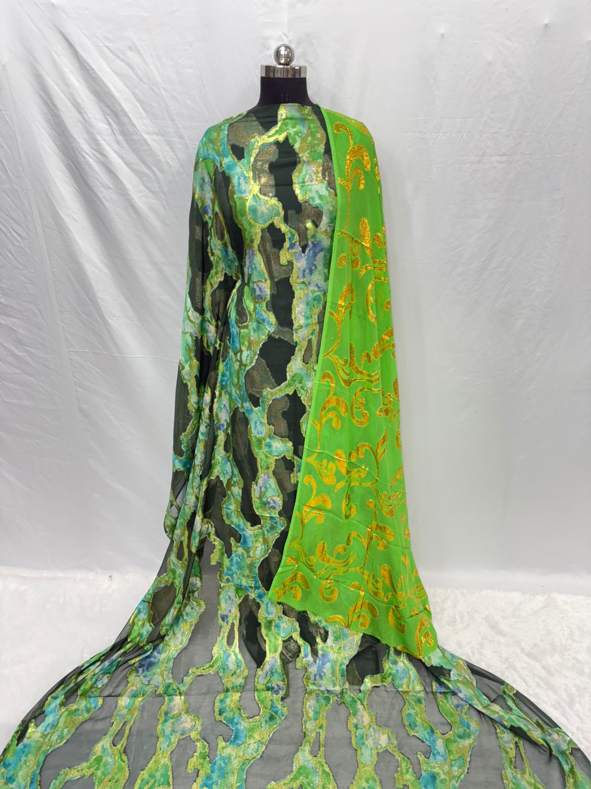 Mannequin wearing a green and black patterned fabric against a white background
