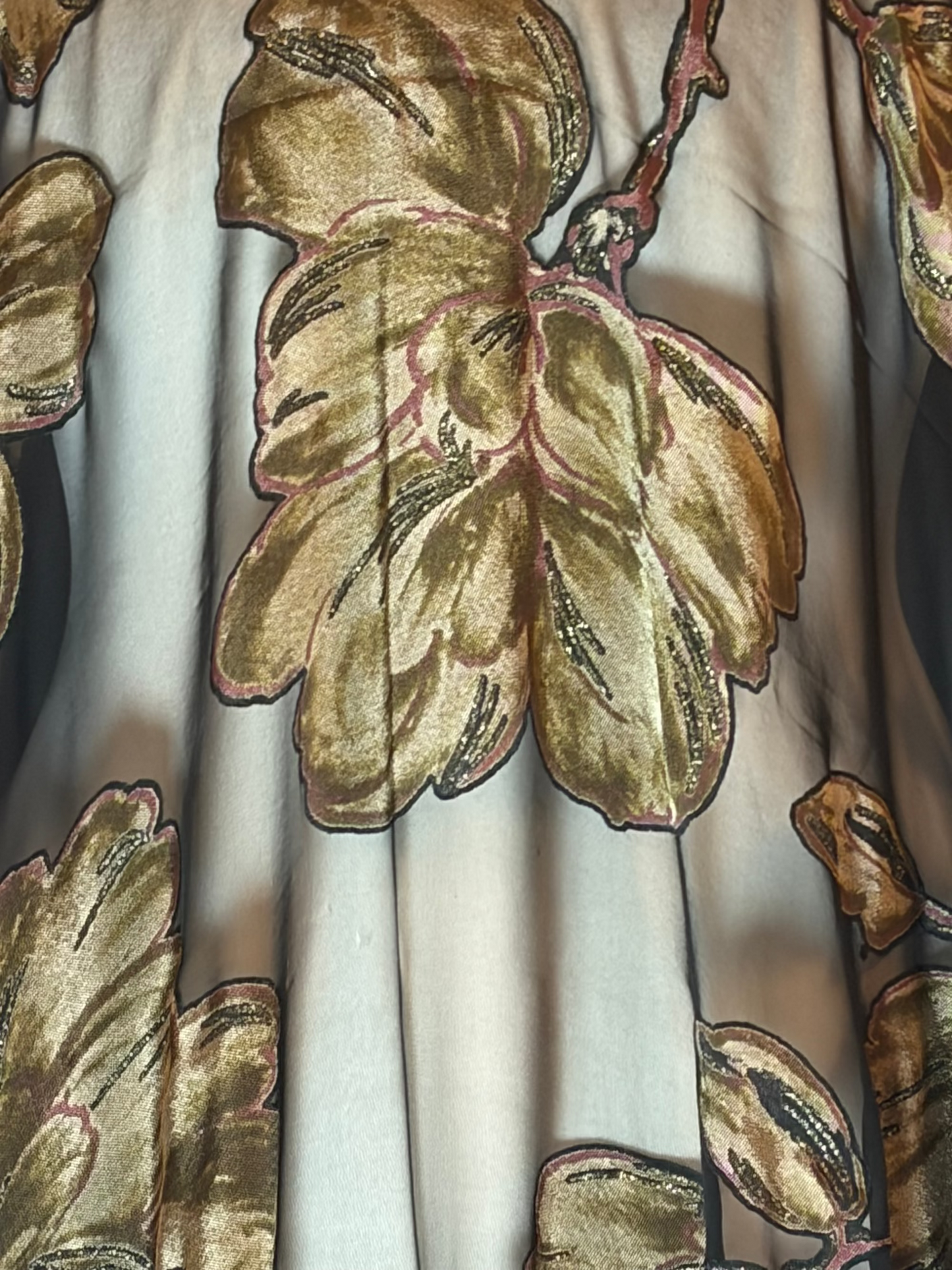 Close-up of a fabric with gold floral embroidery on a white background