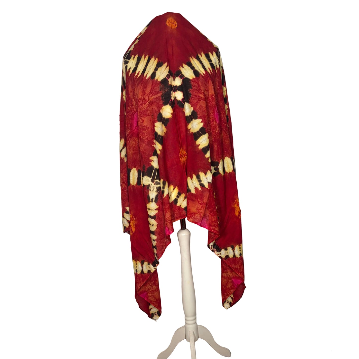 Red and yellow tie-dye shawl on a white stand against a white curtain background.