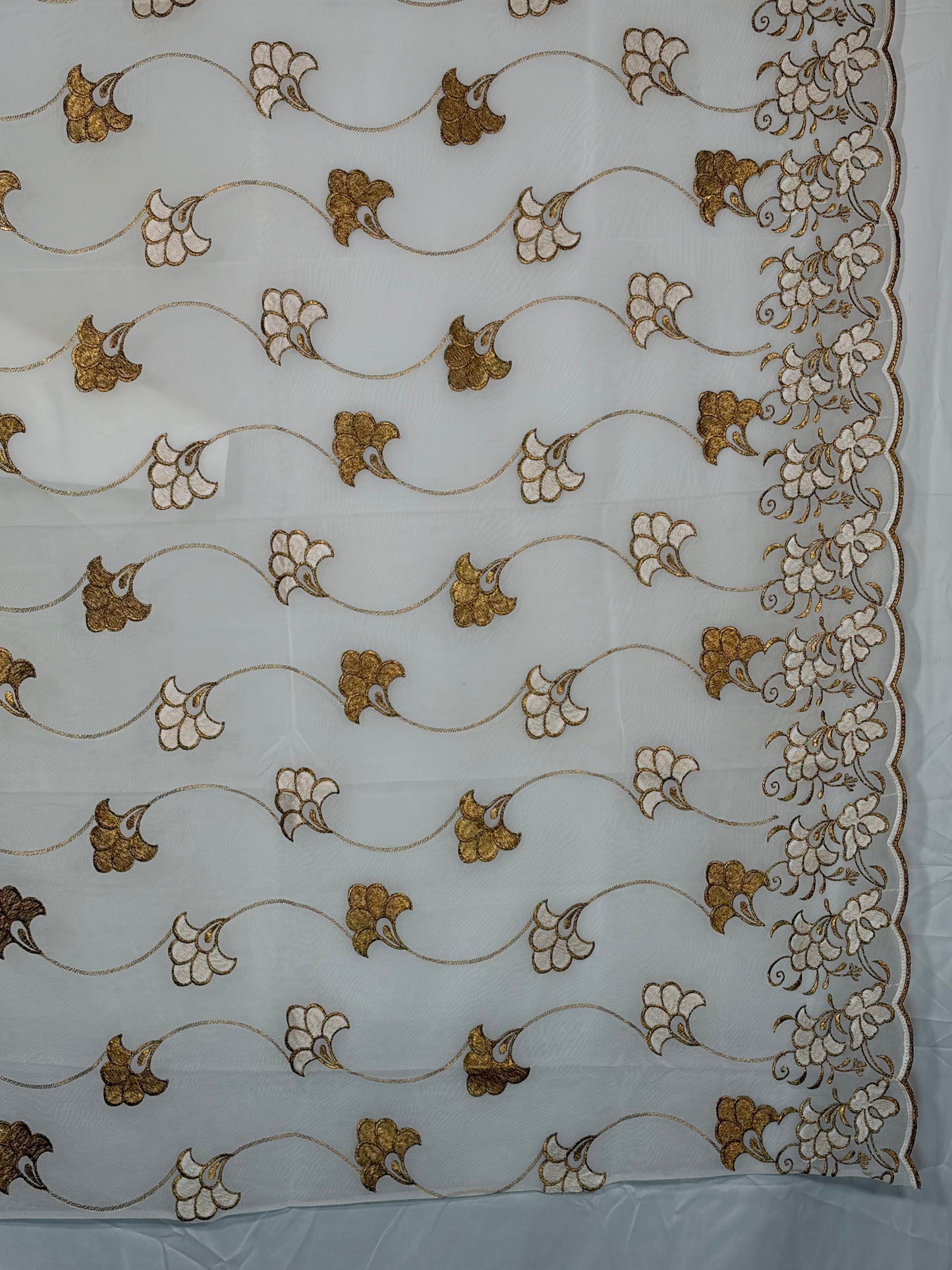 Decorative fabric with gold and white floral patterns on a white background