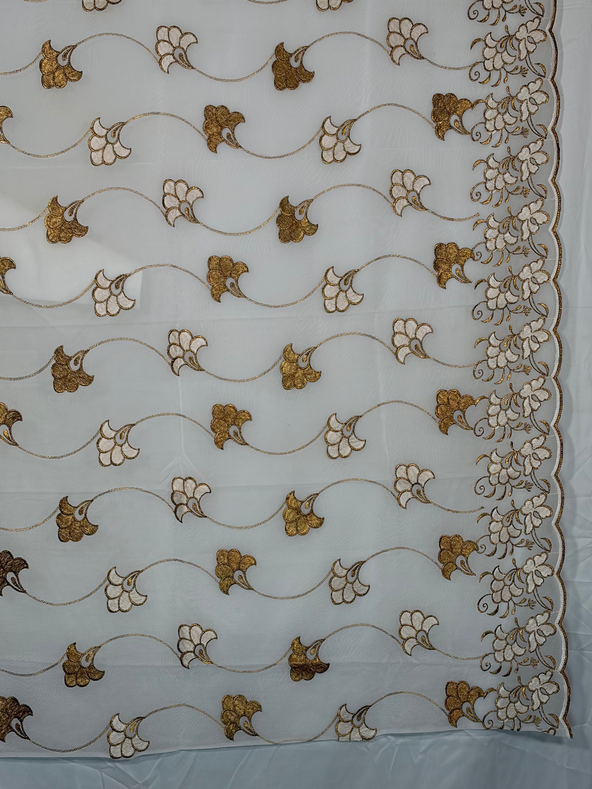 Decorative fabric with gold and white floral patterns on a white background