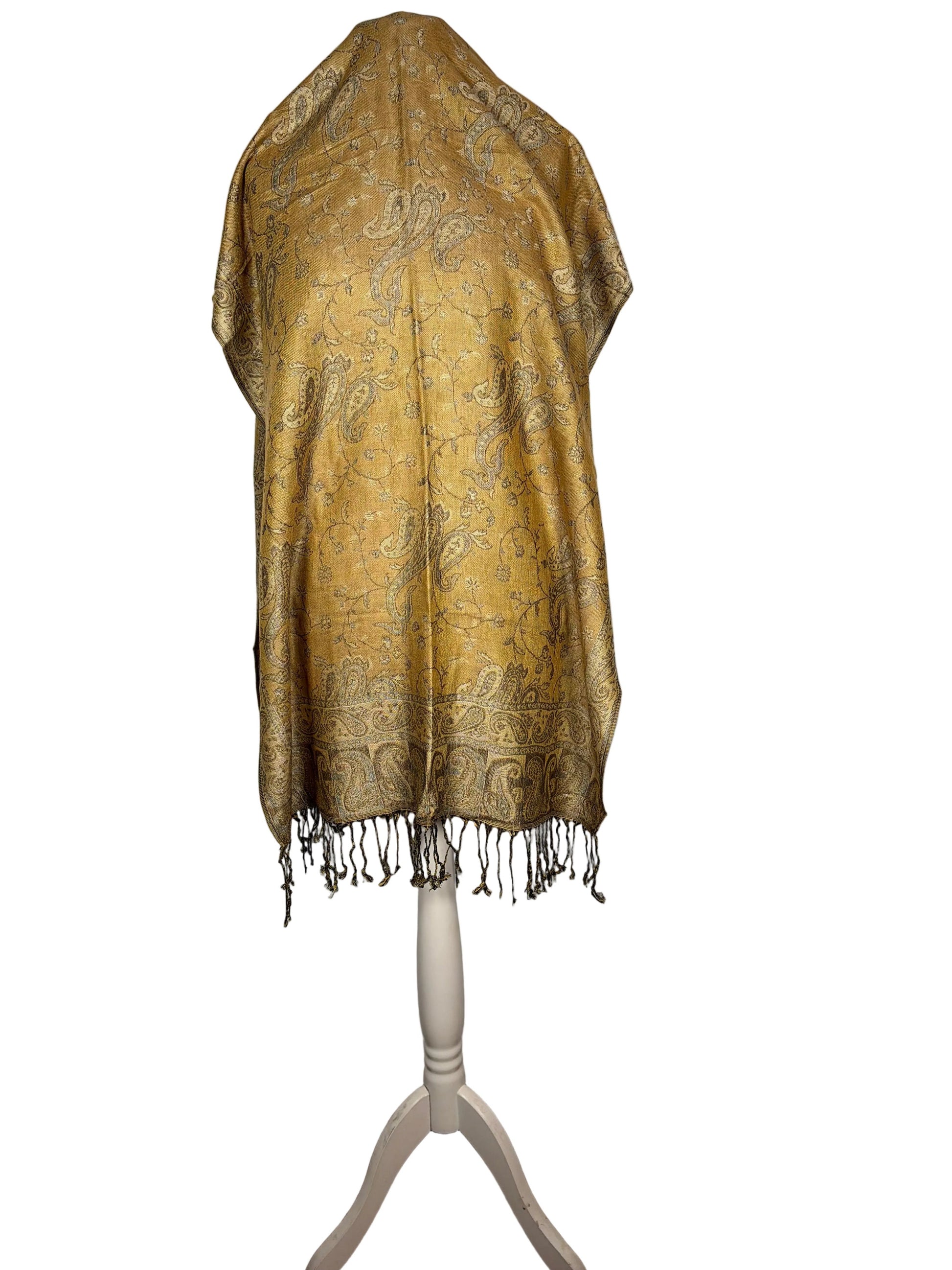 Gold patterned scarf on a white stand against a white background