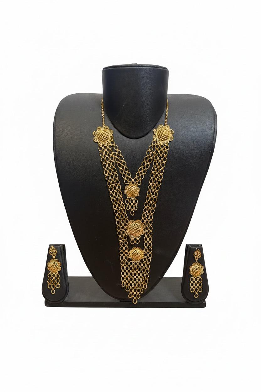 Gold-toned traditional Indian jewelry set featuring a multi-strand chain necklace, matching earrings, and a black display stand on a white background.
