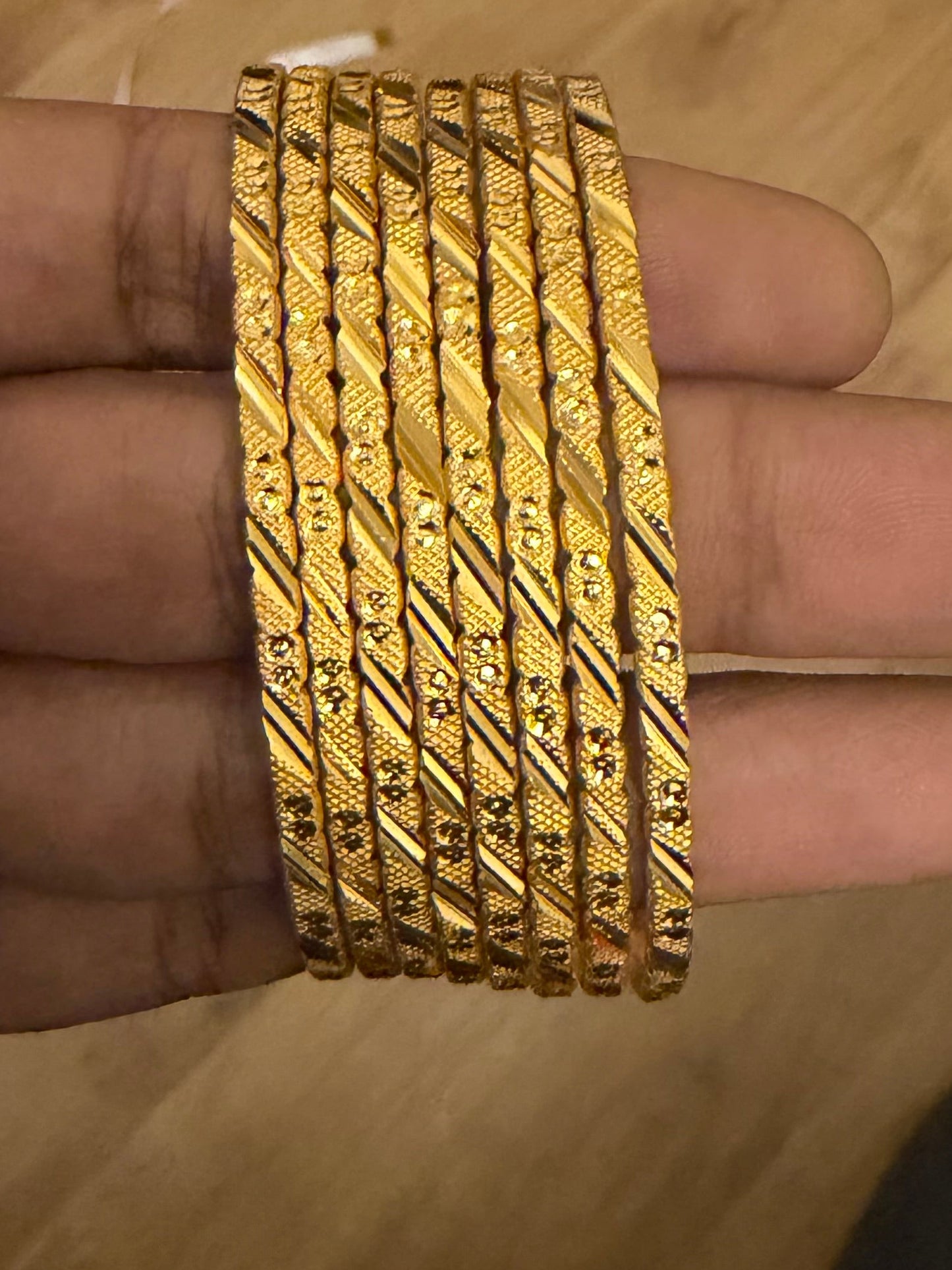Gold bangles on a hand with a blurred background