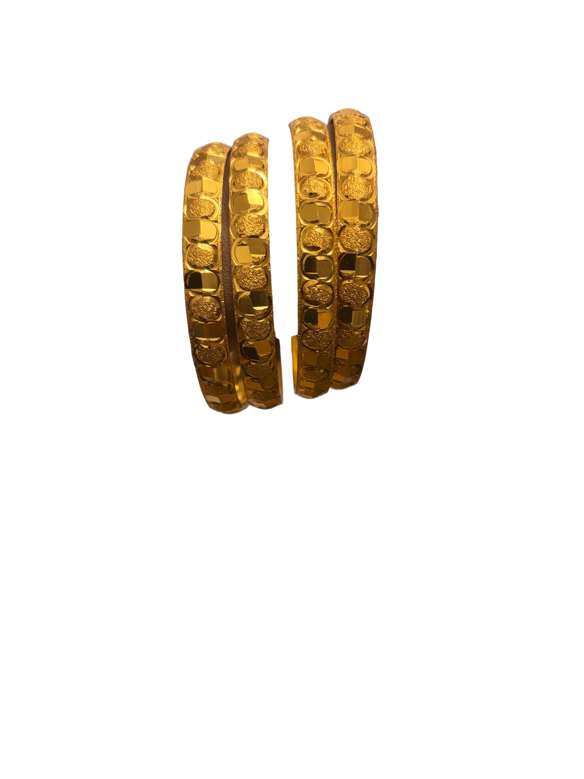 Gold bangles on a wrist with a blurred background