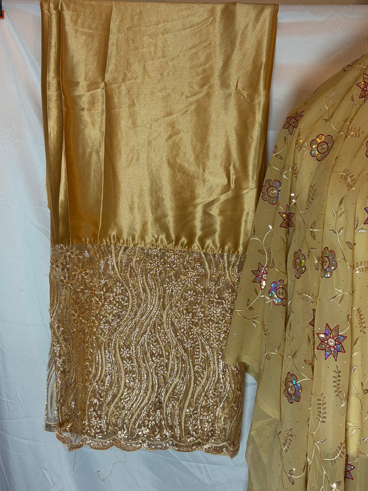 Gold gorogard fabric with floral embroidery on a white background