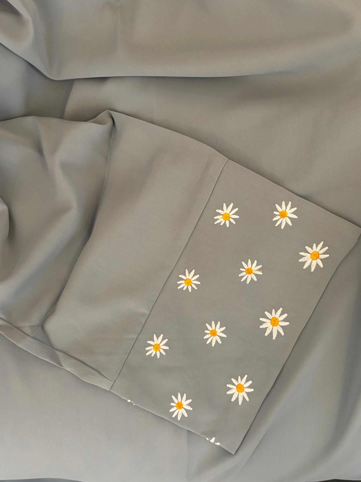 Gray fabric with white daisy patterns on a beige background