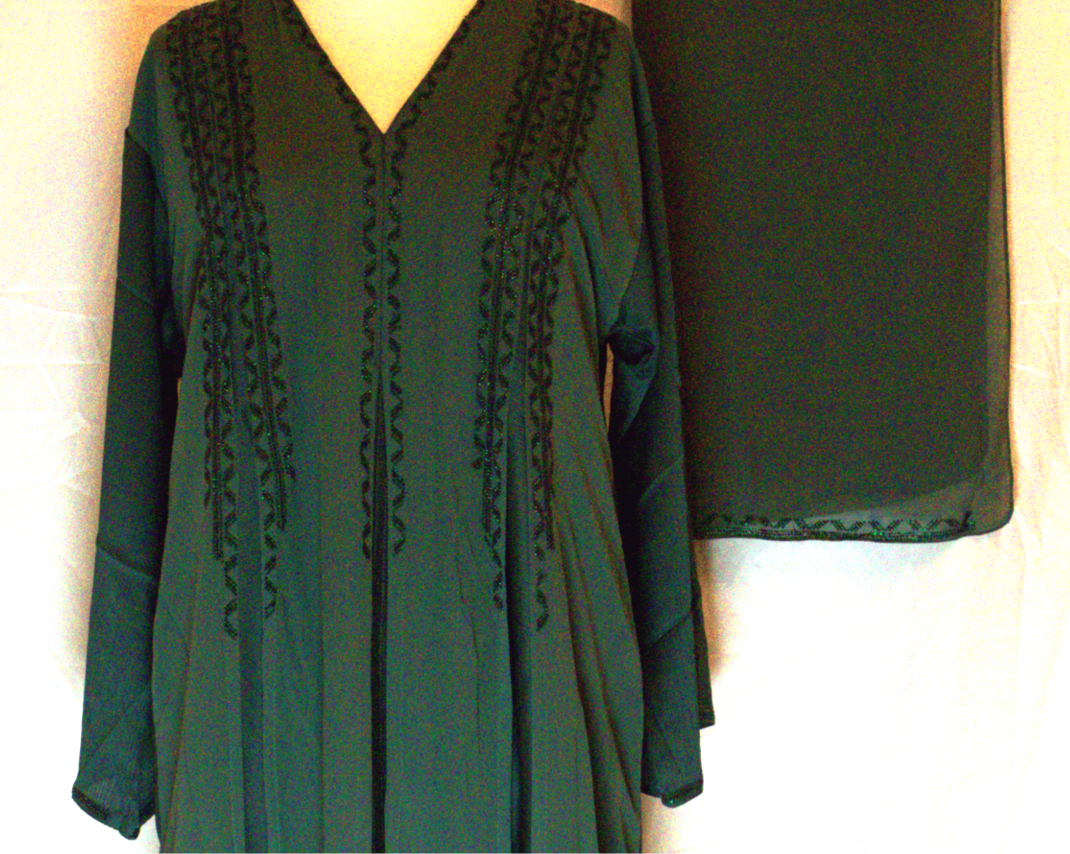 Green dress with black embroidery on a mannequin against a white background