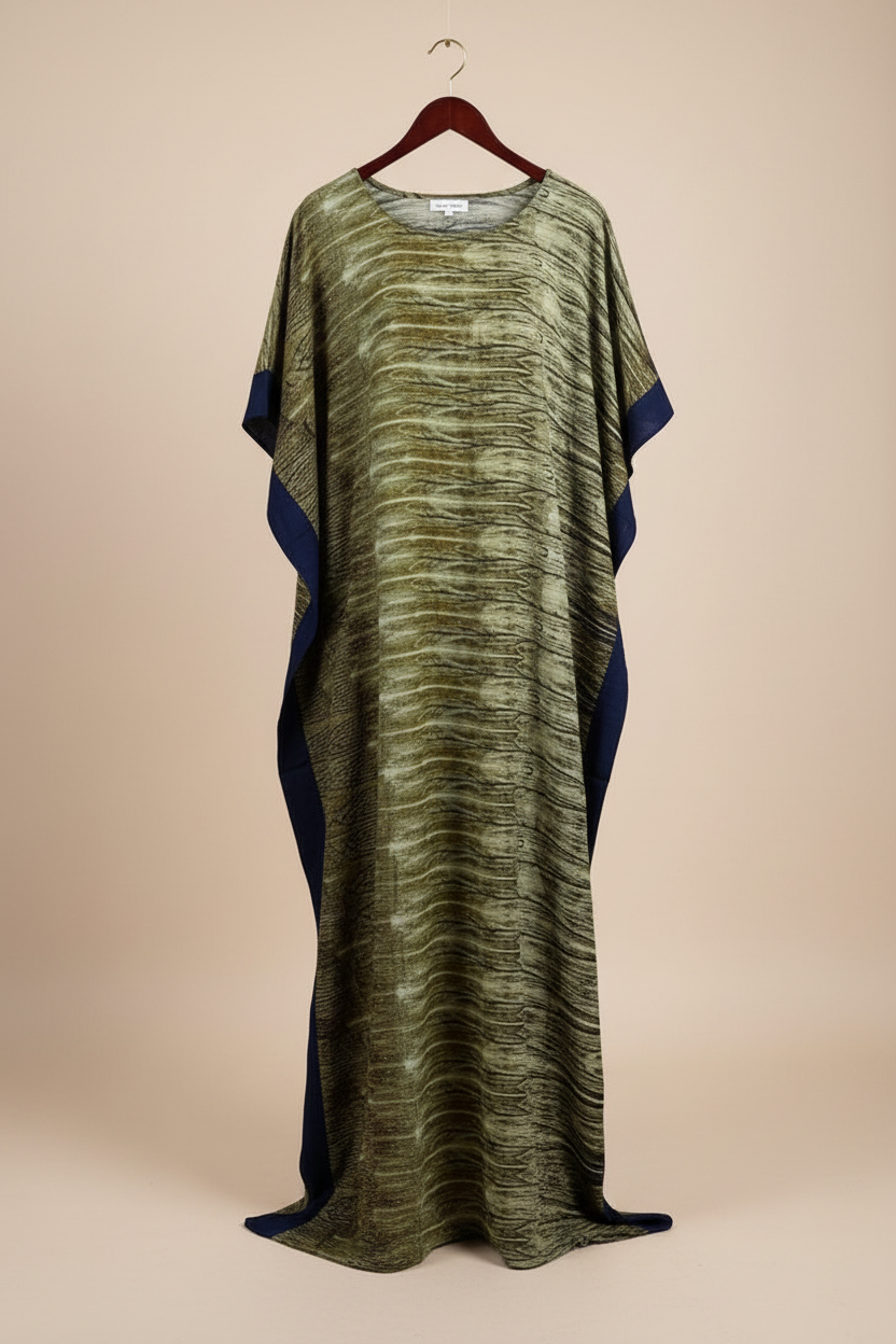 Long, patterned Somali baati dress on a hanger against a beige background