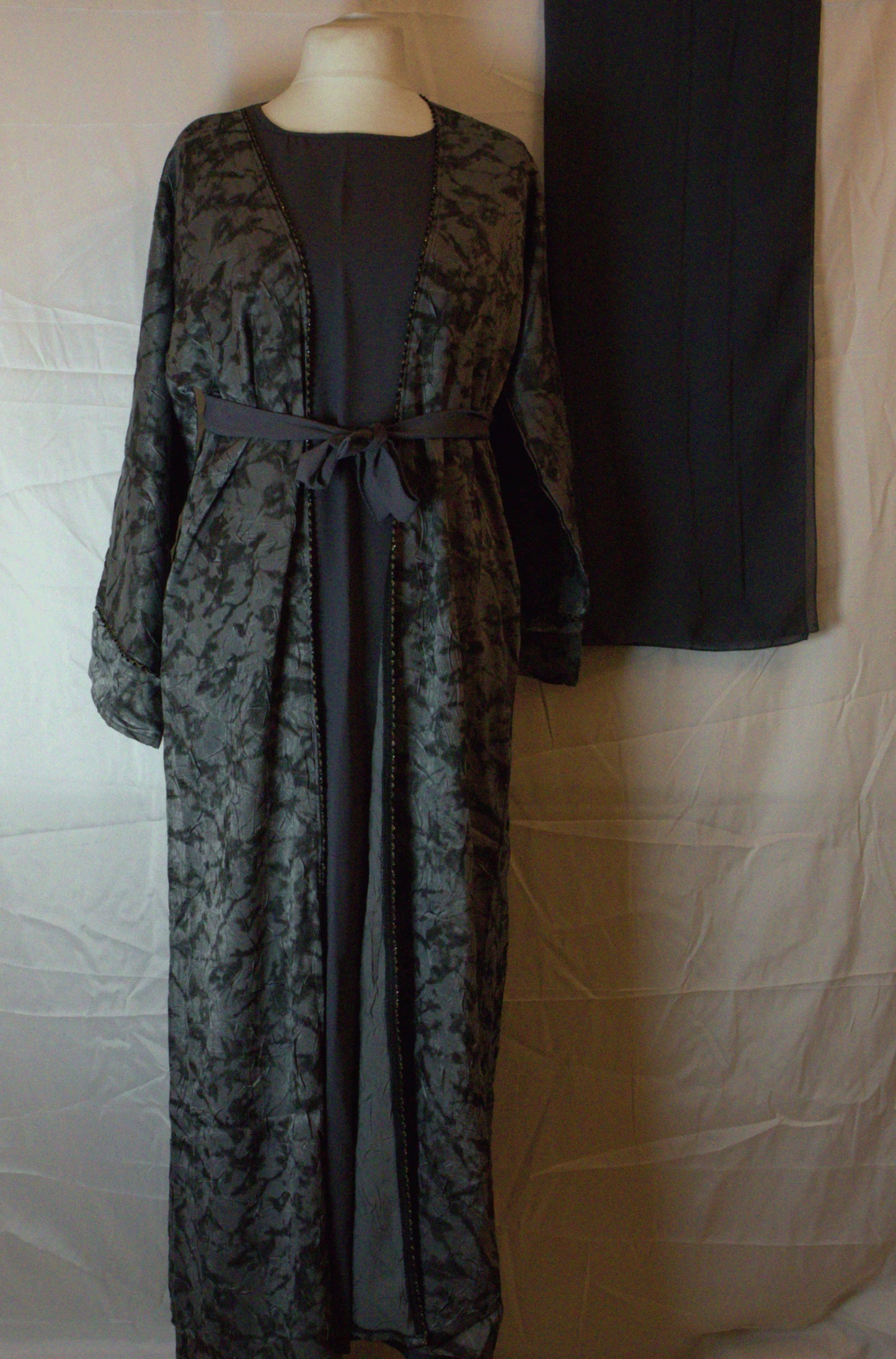 Long patterned two piece abaya on a mannequin against a plain background