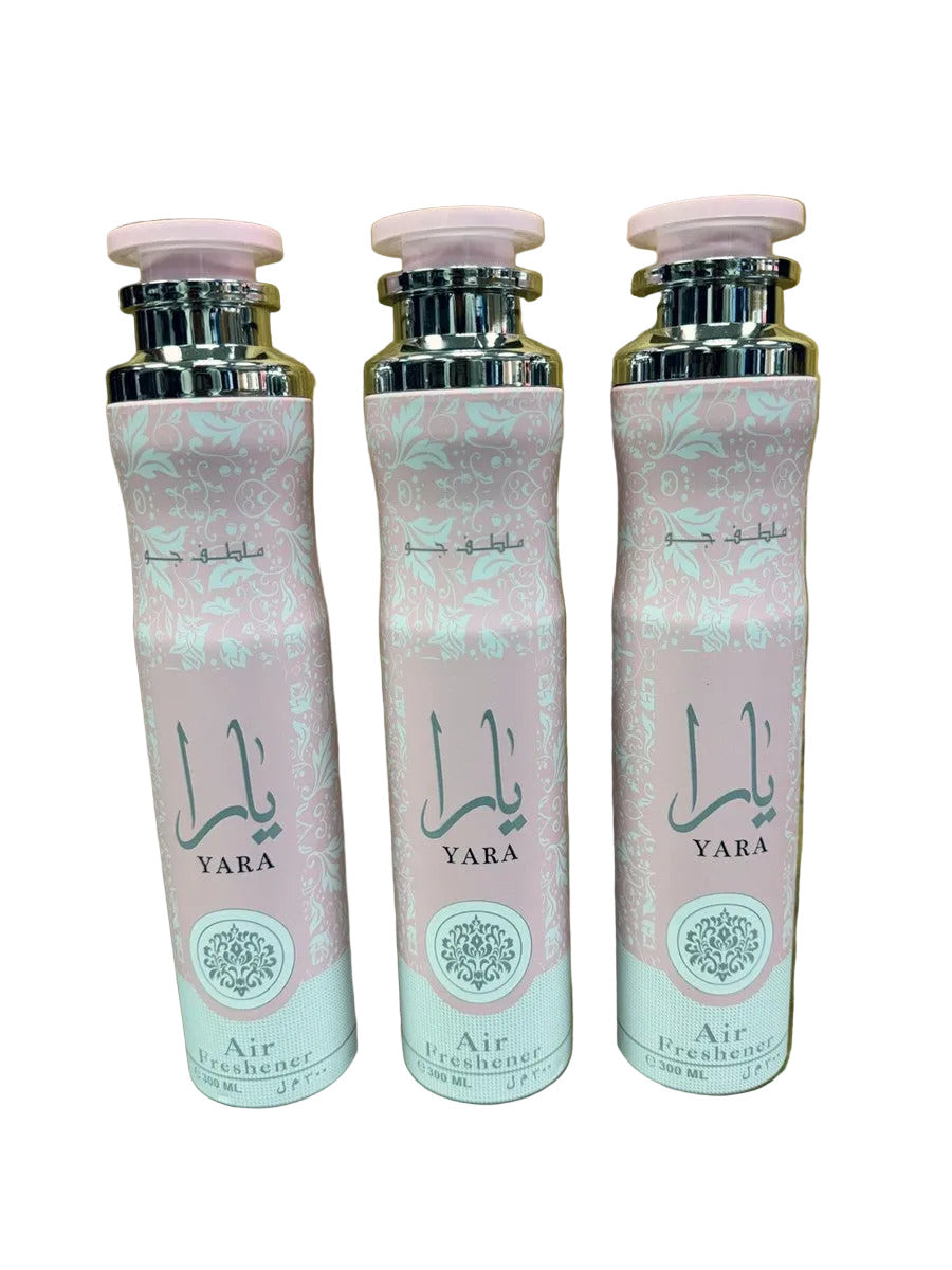 Three YARA Air Freshener bottles with pink and white patterned labels and silver caps, arranged side by side on a reflective surface against a gold textured background.