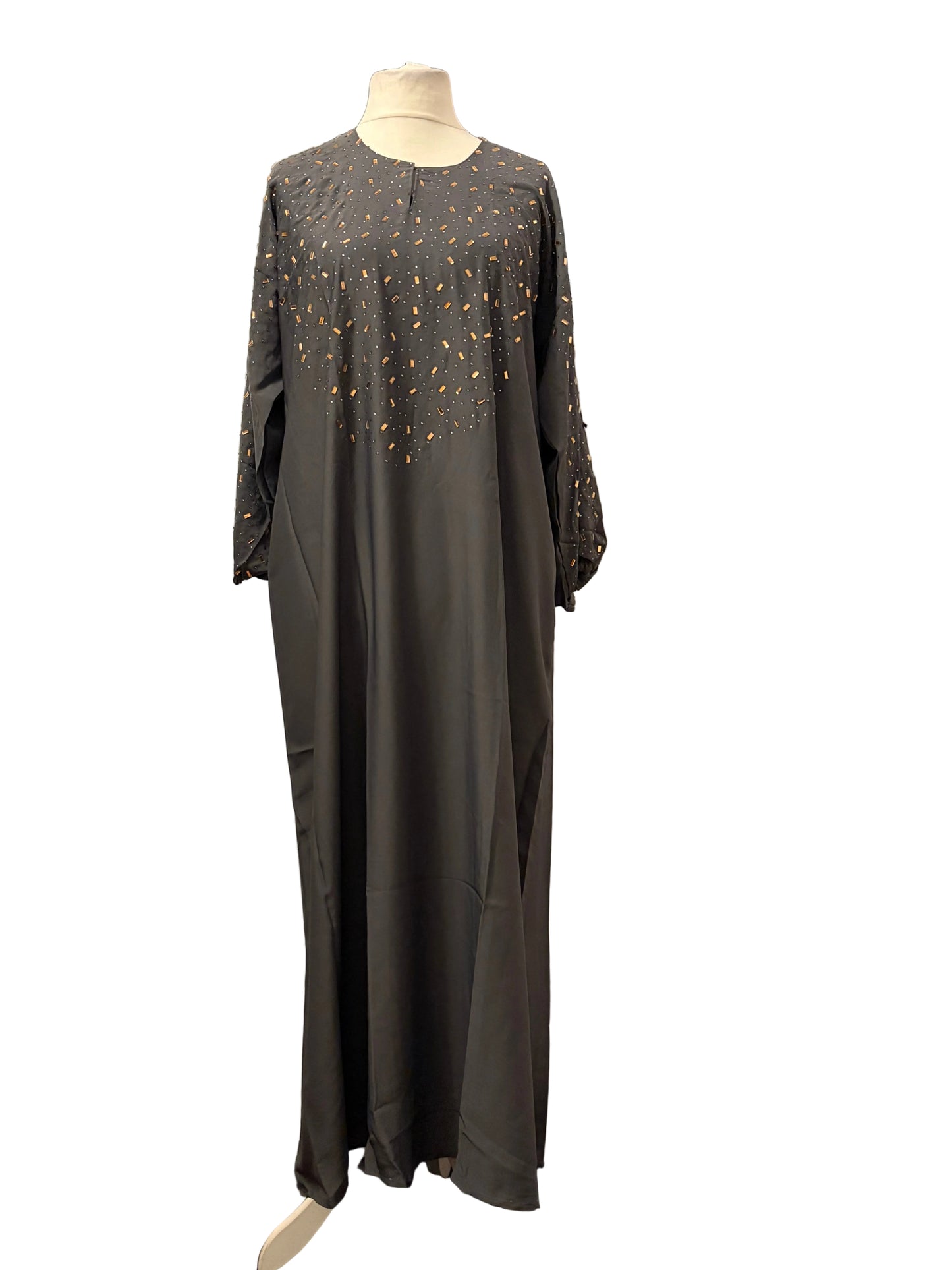 Long dark gray dress with intricate beadwork on a mannequin against a plain background