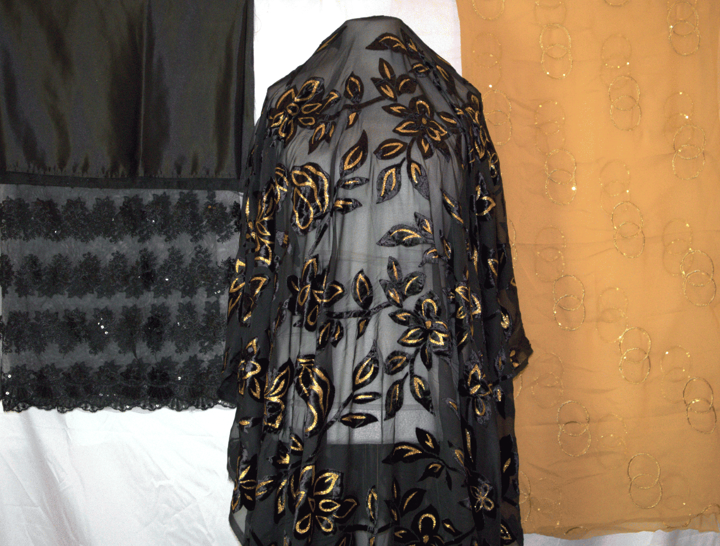 Black embroidered fabric with gold details on a white background