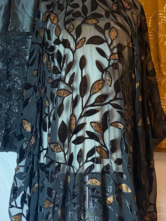 Decorative fabric with leaf pattern on a mannequin against a gold curtain background