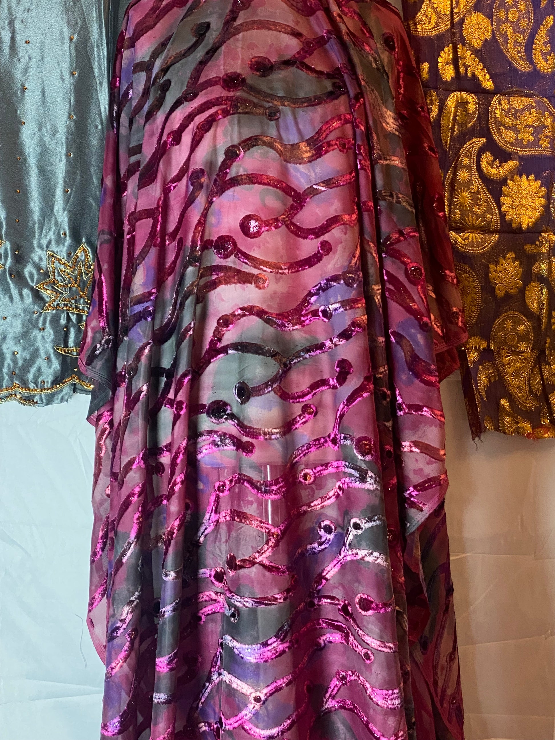 Maqbal dirac fabric with intricate patterns in purple, pink, and gold on a plain background