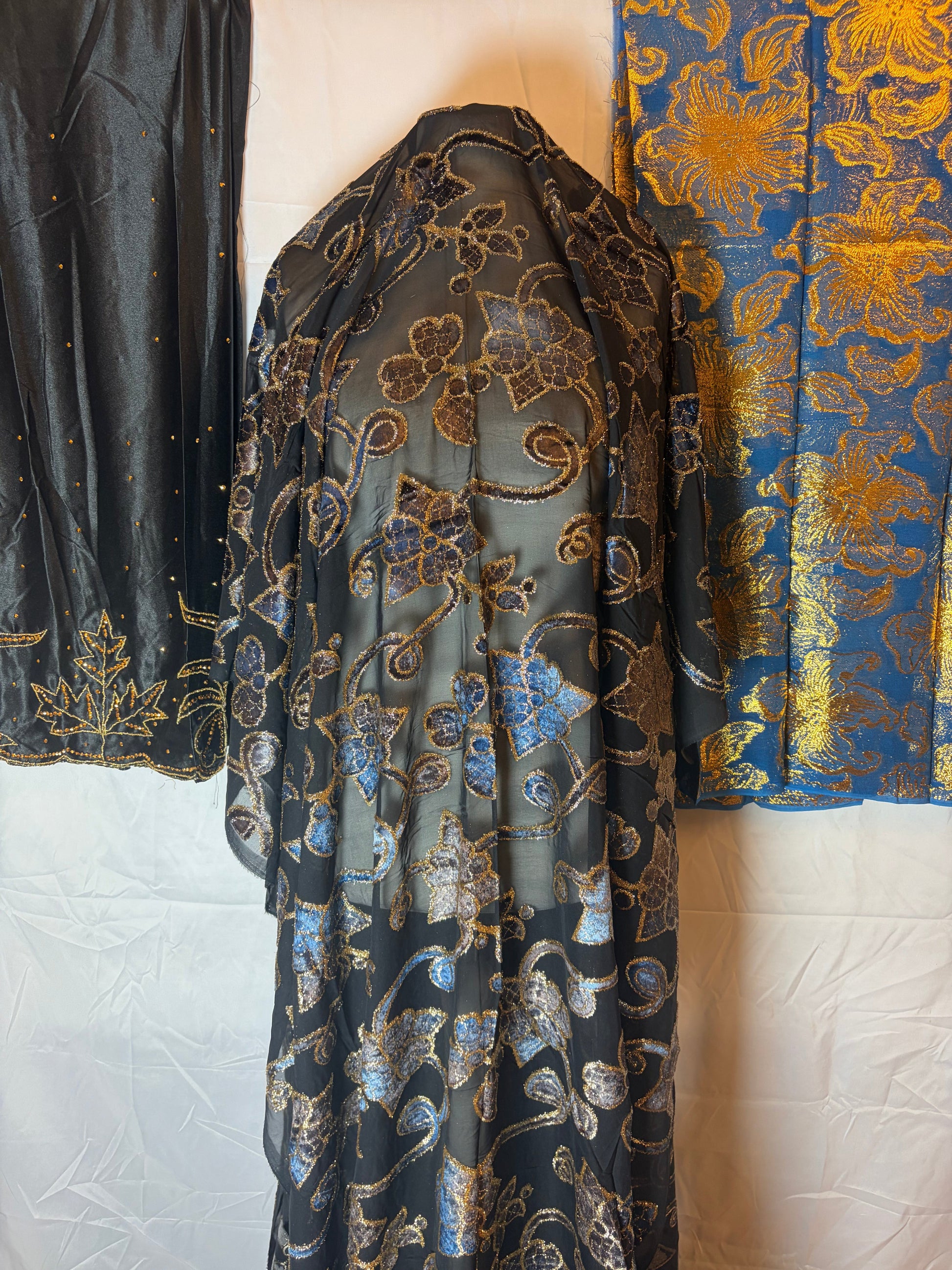 Black Maqbal dirac floral patterned fabric with gold accents on a white background